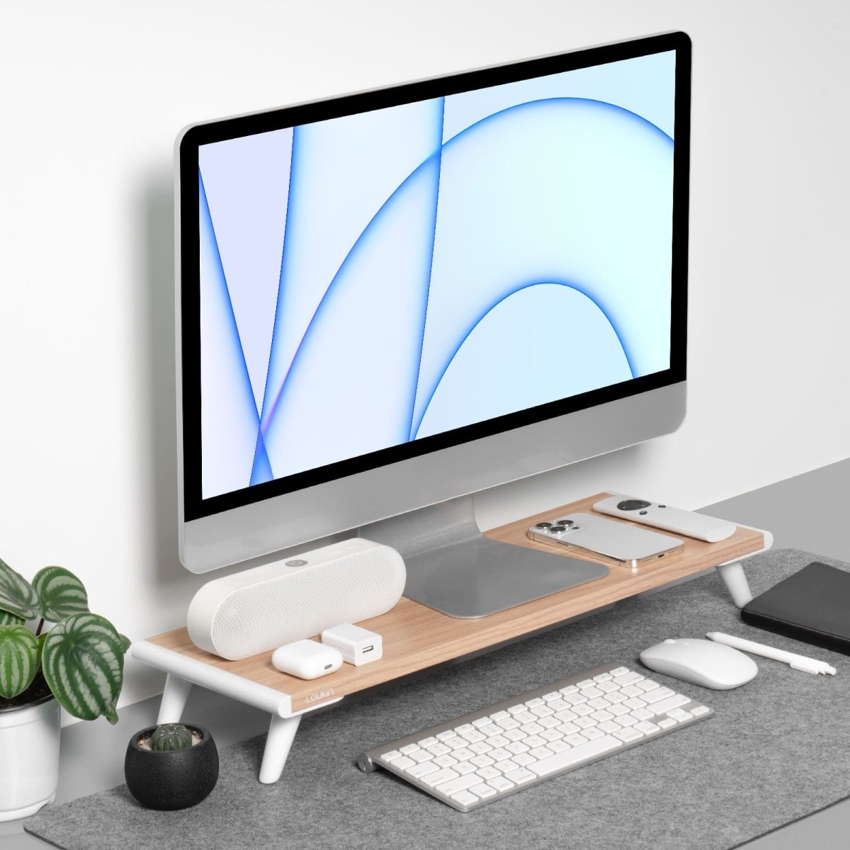 Main product image of the Loukin Single Monitor Stand Riser (S4101). The stand features a light wood grain desktop and white legs in a modern, organized workspace. It is used to elevate a computer monitor, providing storage space underneath for a keyboard and a tidy surface on top for accessories like a smartphone, earbuds, and a speaker.