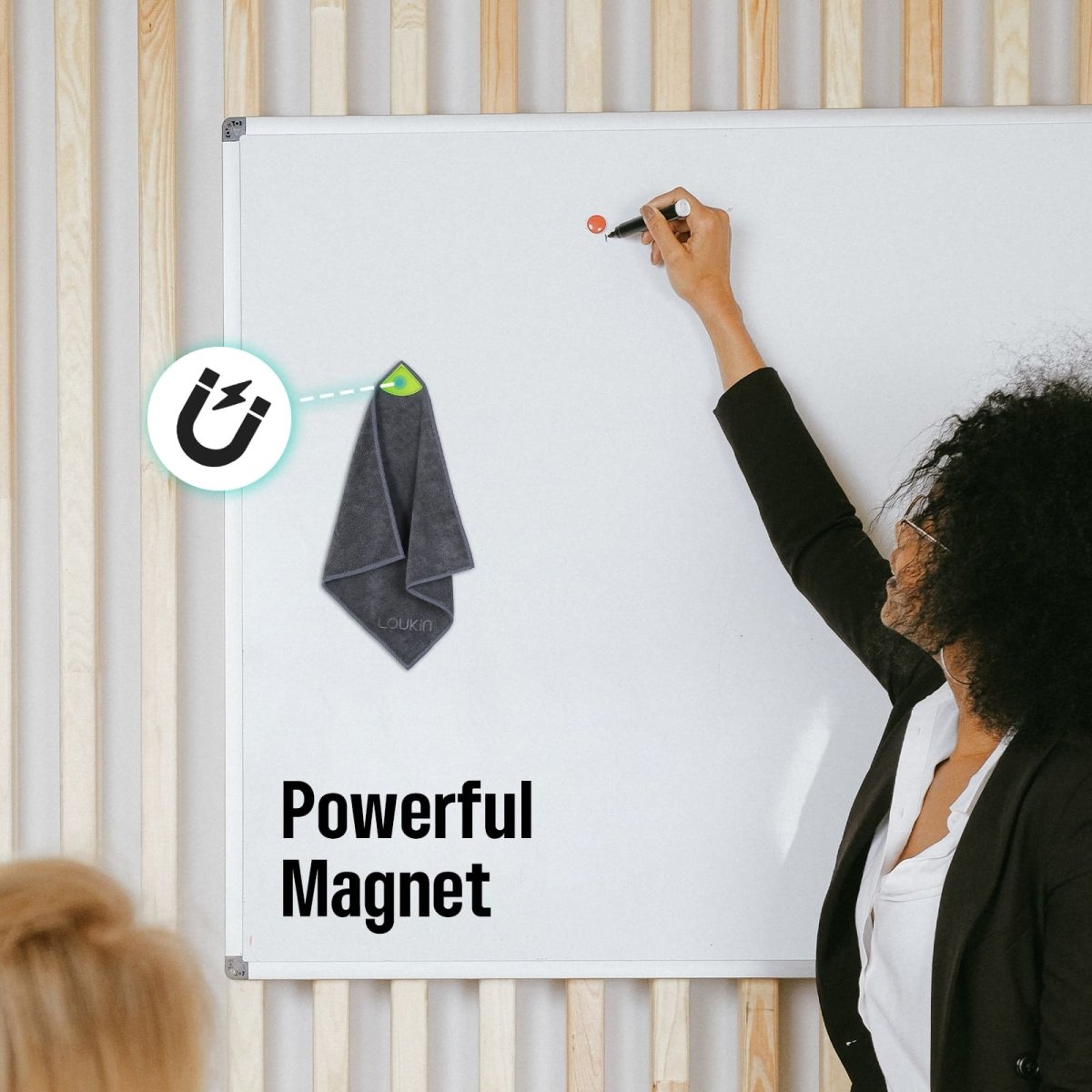 Feature image for the Loukin Magnetic Cleaning Cloth (W3306K), highlighting the "Powerful Magnet" function. The photo shows the dark grey microfiber cleaning cloth, secured by its magnet and bright green loop, hanging neatly on a large white magnetic whiteboard. A person is shown writing on the board, demonstrating the convenience of having the cloth easily accessible.