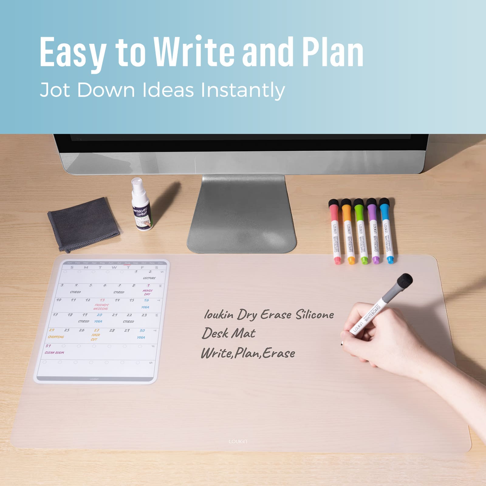 loukin W1402K Dry Erase Silicone Desk Mat in use on a wooden desk beneath a monitor, highlighting the "Easy to Write and Plan" and "Jot Down Ideas Instantly" features. A hand is shown writing notes directly onto the mat next to the built-in calendar/planner template. Cleaning accessories and colored markers are visible nearby.
