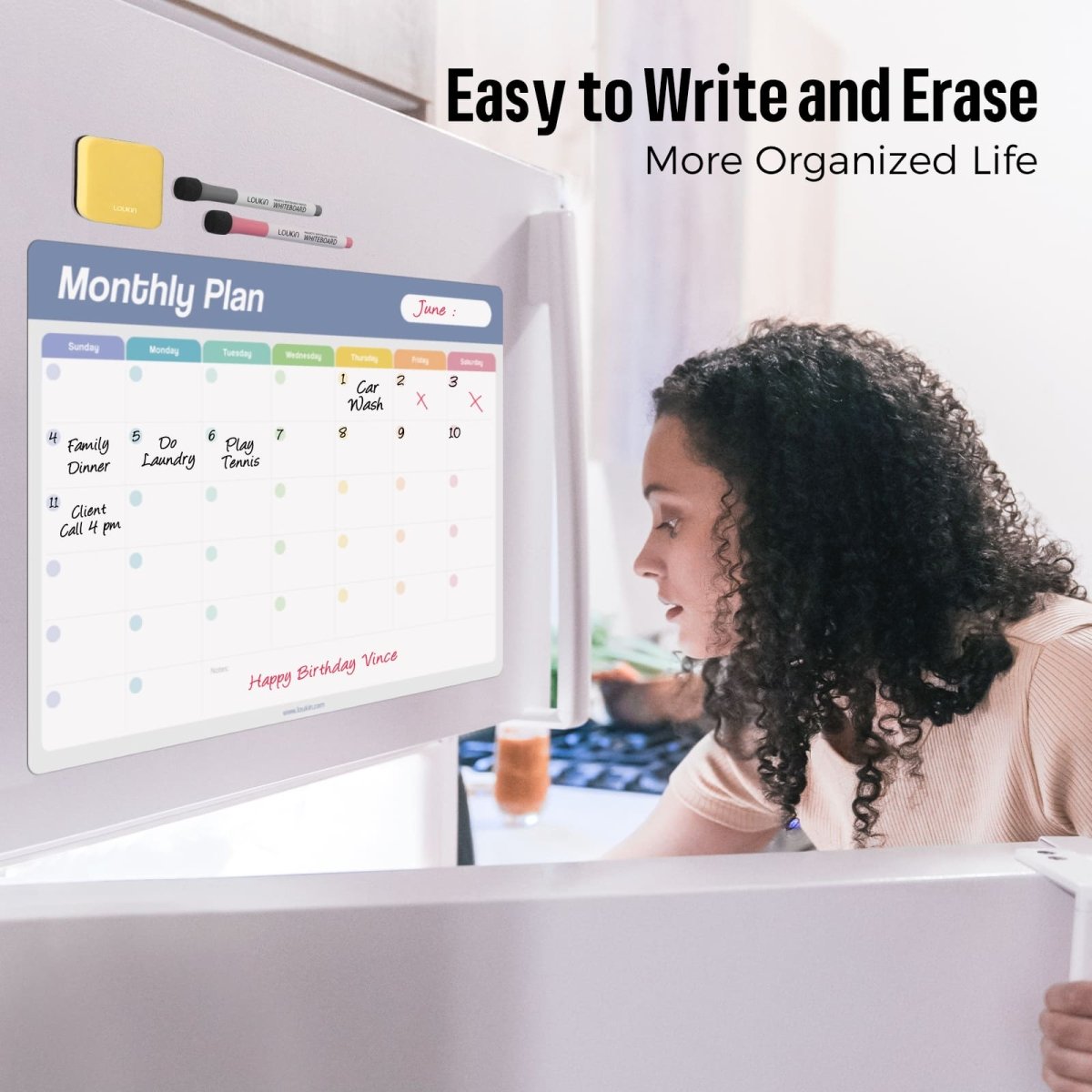 An in-use image showing a woman looking at the LOUKIN Static Cling Dry Erase Monthly Calendar (model W1303K) with "June" written on it, which is attached to a refrigerator. The image highlights the benefits: **"Easy to Write and Erase"** and living a **"More Organized Life"**. A yellow mini eraser and markers are also visible on the fridge.