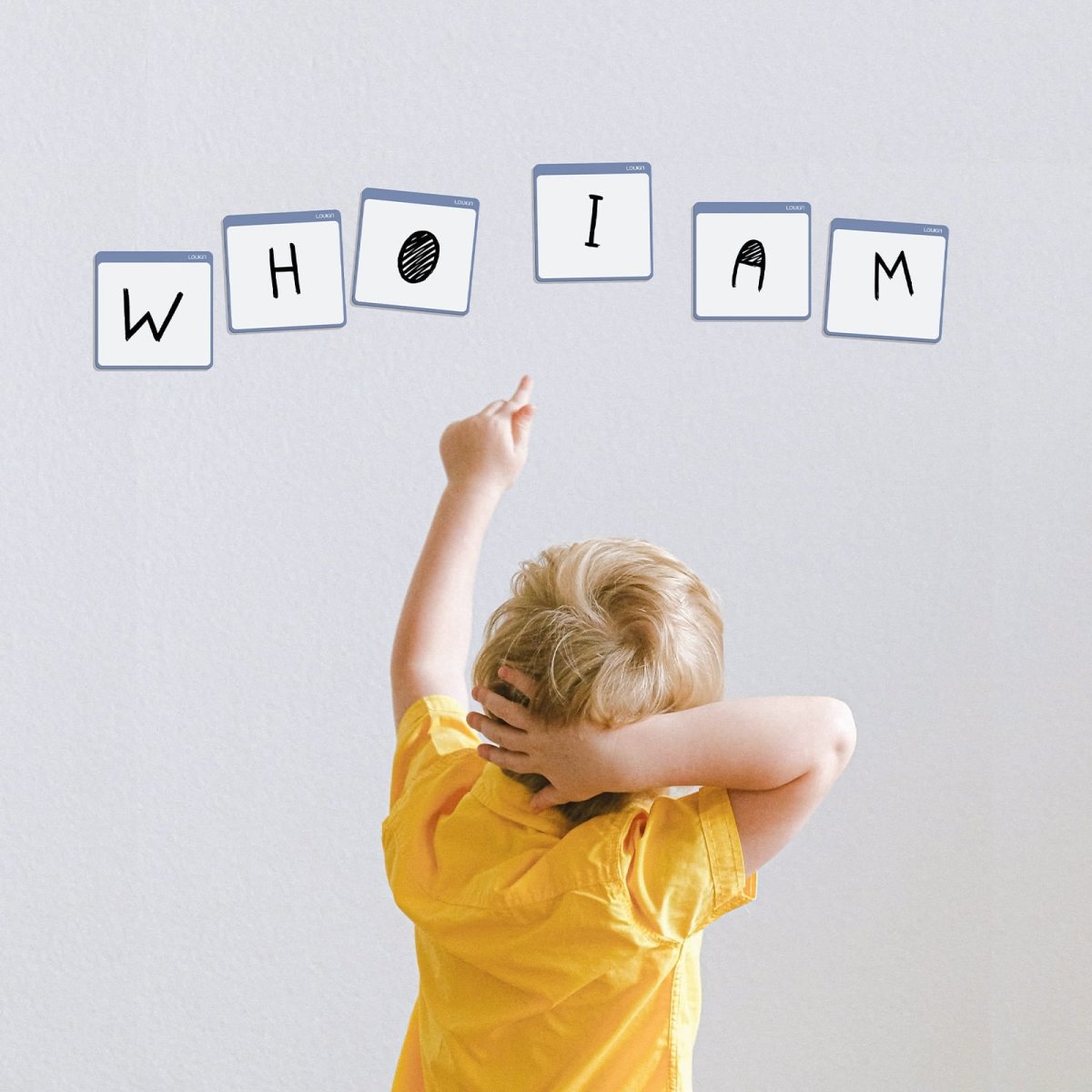 A lifestyle image showing a young boy pointing at six LOUKIN **Mini Dry Erase Note** boards (model W1309K) adhered to a white wall. The memo boards are used to display letters that spell "W H O I A M," highlighting the product's use for **children's learning, spelling games, and creative interactive activities**.