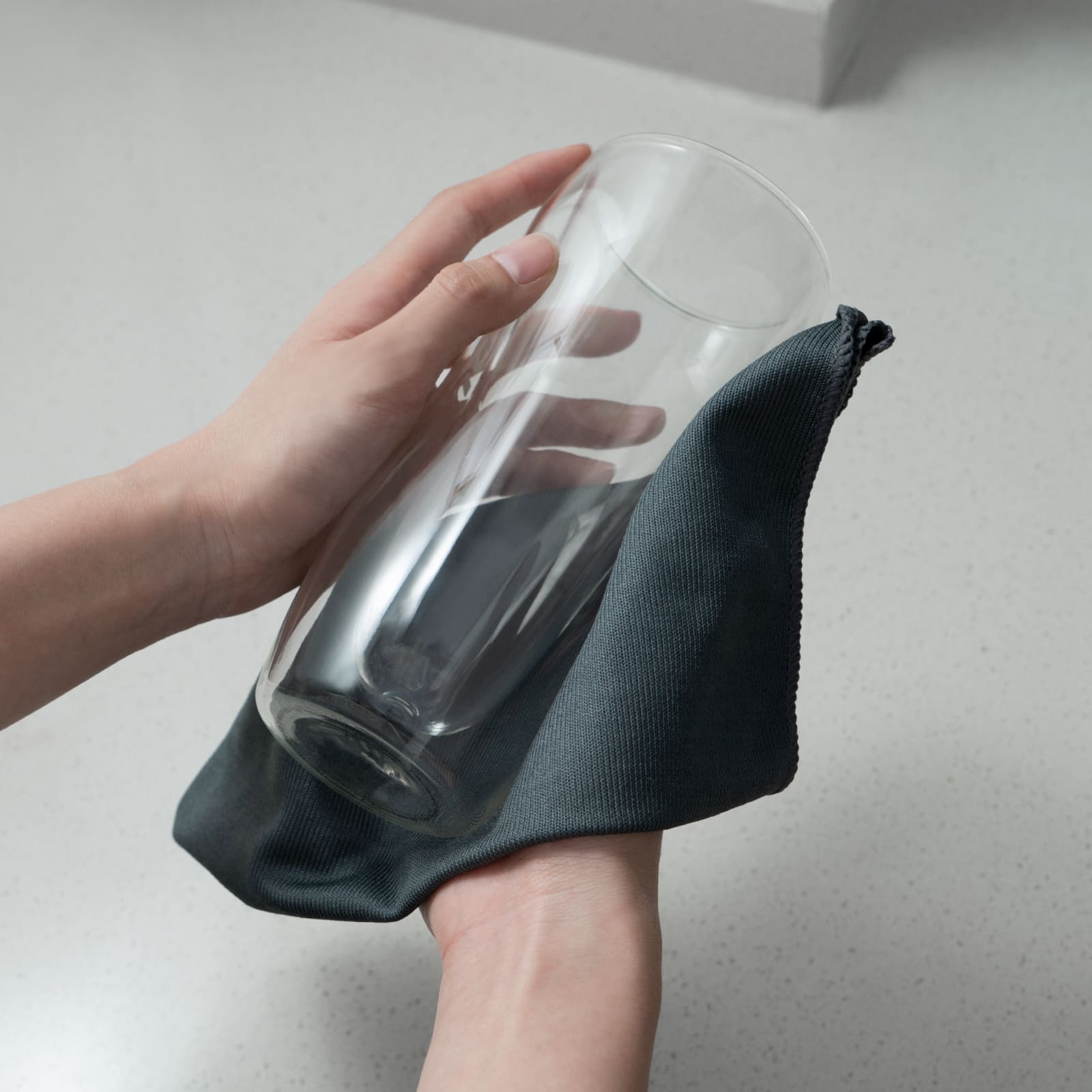 An image showing a hand using the LOUKIN microfiber cleaning cloth, SKU W3301, to wipe a glass surface, demonstrating its use on various smooth surfaces.