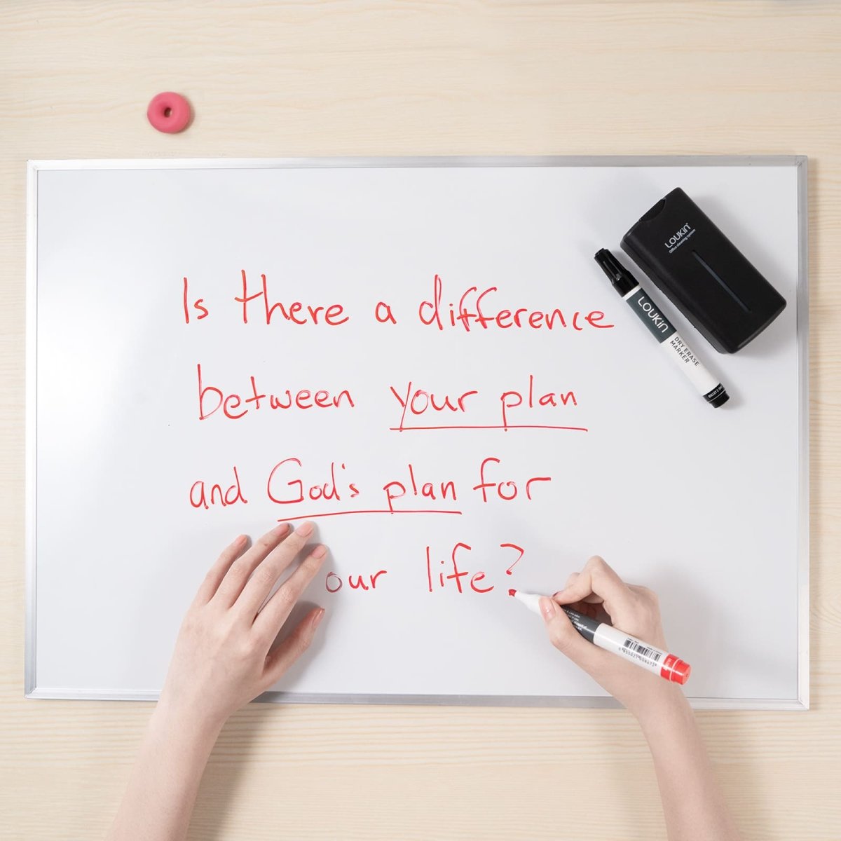 A product image of a person's hands on a whiteboard. A red marker is used to underline the words "God's plan" in the sentence, "Is there a difference between your plan and God's plan for our life?" The LOUKIN all-in-one dry erase eraser, SKU W3505K, and a black dry erase marker are visible at the top of the board.
